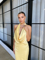 Alice Dress by Lexi, in butter yellow colour, deep cowl neckline, luxe satin fabric, halter tie-up back with adjustable strap, sleek straight fit with back split. Hire for weddings, special events, formal events, school balls.
